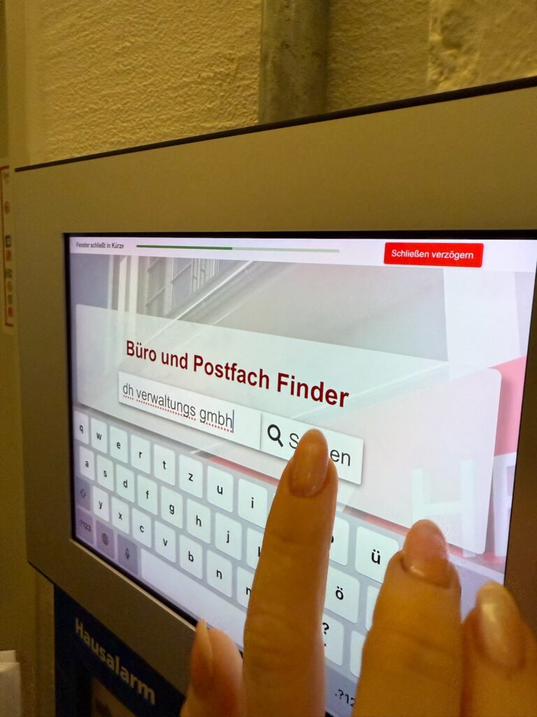Person nutzt den Büro- und Postfach-Finder auf einem Touchscreen.